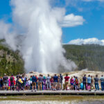 Tourists watching the Old Faithful erupting in Yellowstone National Park, USA